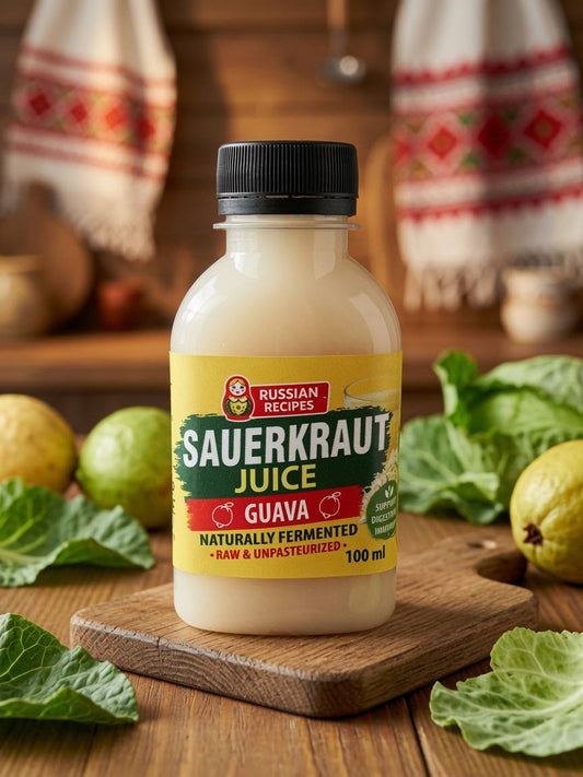 A bottle of Russian Recipes Sauerkraut Juice Guava, 100 ml, displayed on a wooden cutting board with fresh green leaves and lemons in a rustic kitchen setting.
