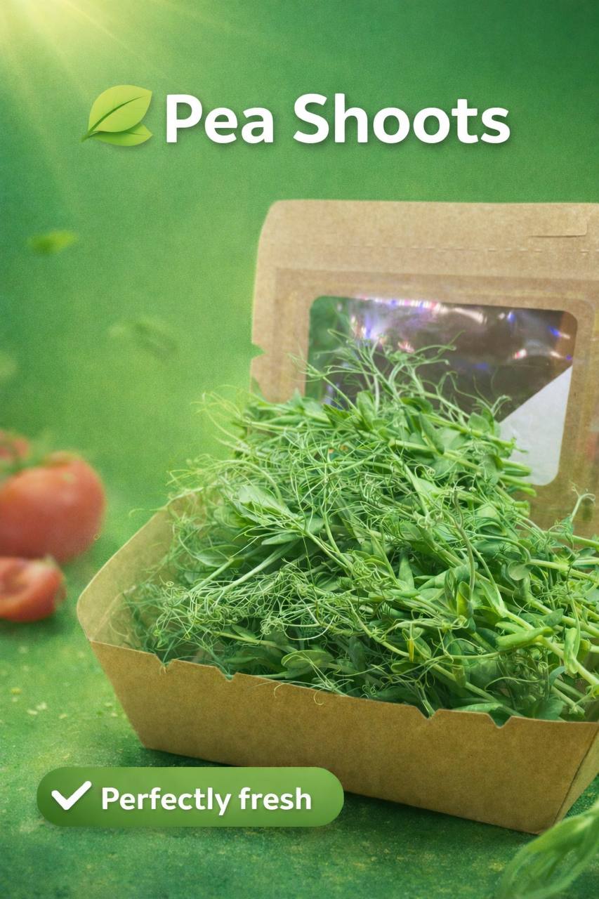 Packaged pea shoots with a green background and tomatoes on the side.