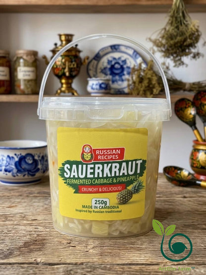 A clear plastic tub of Russian Recipes Sauerkraut (fermented cabbage and pineapple) with a yellow label, set on a rustic wooden table with traditional kitchenware in the background.